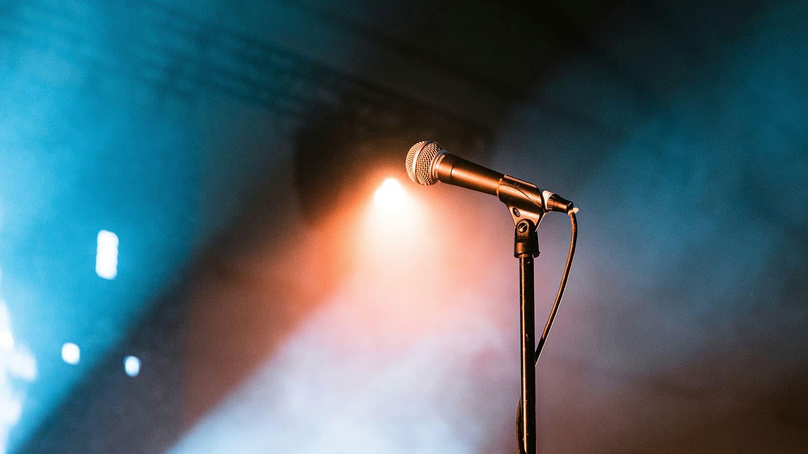 A microphone on an empty comedy club stage, lit by a single spotlight